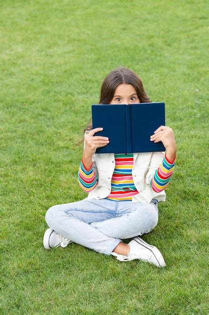 Premium Photo Teen Girl Behind Book Sitting On Grass Reading Book