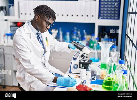 African American Man Scientist Using Microscope Writing Report At