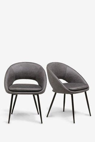 Two Grey Chairs Sitting Next To Each Other On Top Of A White Surface