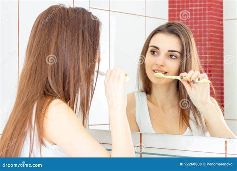 Beautiful Young Girl Brushing Her Teeth In Front Of The Mirror Stock