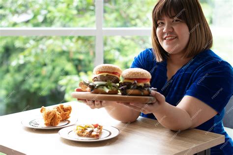 Premium Photo Hungry Overweight Woman Holding Hamburger On A Wooden