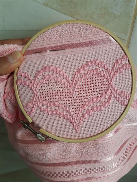 A Person Holding A Pink Bag With A Cross Stitch Heart Design On The