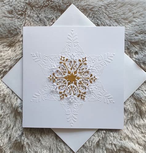 A White And Gold Snowflake Card On Top Of A Furnishing Area