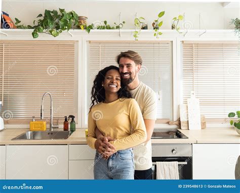 Multiethnic Heterosexual Couple Smiling Hugging And Looking At Camera