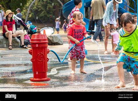 Young Chlidren Playing In Vancouver Park With Water From Hose And Fire