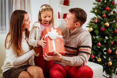 Jonge Familie Viert Kerst Thuis Vader En Moeder Geven Een Kindercadeau Stock Foto Image Of