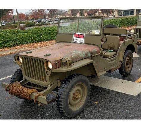 An Old Army Jeep Is Parked In A Parking Lot Next To Another One With A