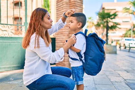 Mãe latina penteando a mão seu filho estudante na cidade Foto Grátis