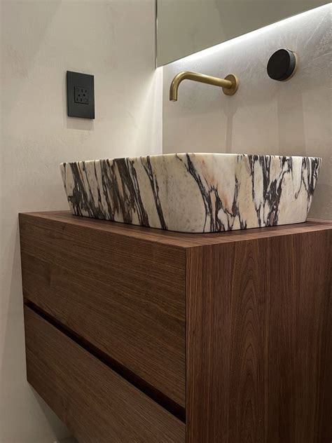 a marble sink sits on top of a wooden cabinet