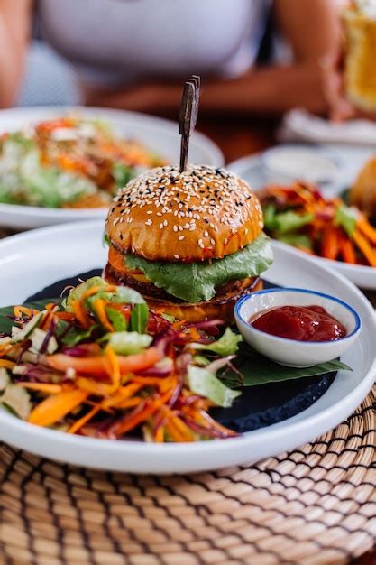 Hamburguesa jugosa con verduras frescas en el café en la mesa Foto Gratis