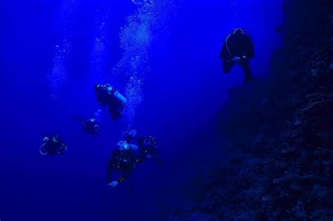 Mergulhadores subaquáticos em profundidade no fundo do mar azul Foto