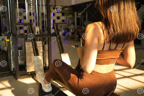 Young Beautiful Woman Performing Dorsal Exercises On A Rowing Machine