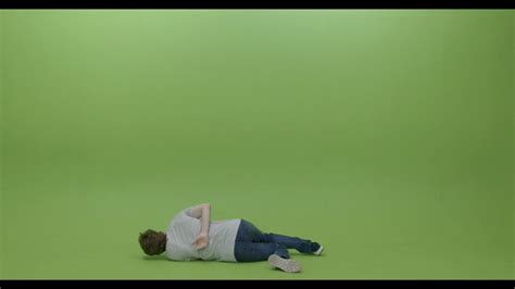 a person laying on the ground in front of a green screen