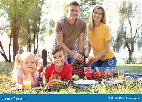 Familia Feliz Que Tiene Comida Campestre En Parque Foto De Archivo