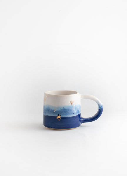 A Blue And White Coffee Mug Sitting On Top Of A White Table Next To A Wall