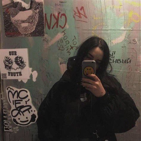 A Woman Taking A Selfie In Front Of A Wall Covered With Graffiti