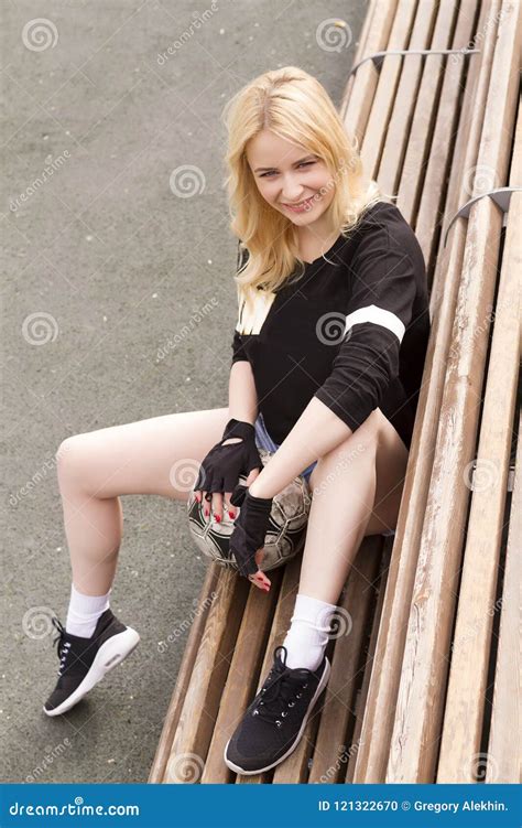 A Menina Senta Se No Banco No Campo De Futebol A Bola Foto De Stock