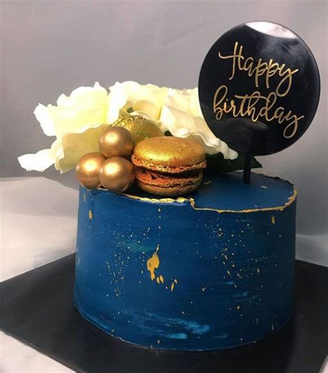 A Blue Cake With Gold Decorations And A Happy Birthday Sign Sitting On