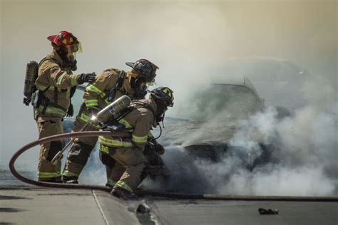 Firefighters Extinguish A Car Fire As Their Captain Looks On