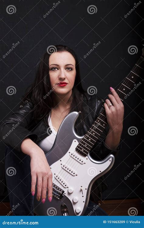 Beautiful Dark Girl Playing Guitar In Rock Style On A Black Background