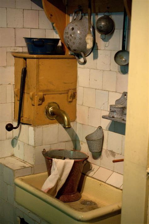 An Old Fashioned Kitchen Sink With Dirty Dishes Hanging On The Wall