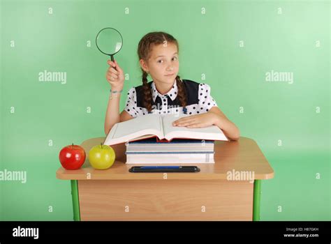 Fille Dans Un Uniforme Scolaire Assis à Un Bureau Avec Une Loupe Isolé