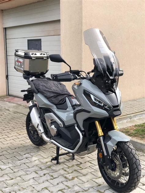 A Silver Motorcycle Parked On Top Of A Brick Road Next To A Garage Door