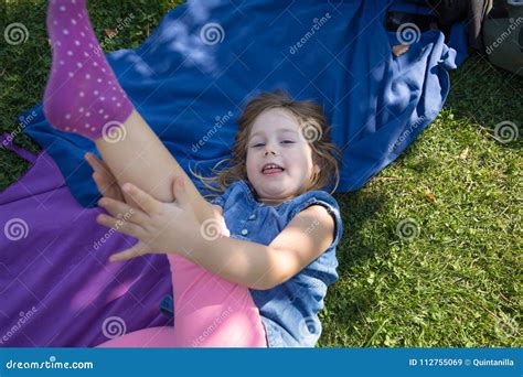 Petite Fille Se Situant En Parc Semblant La Jambe émouvante Image stock