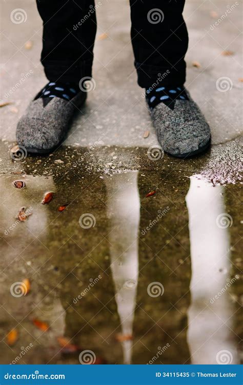 A Man S Feet And Legs Reflected In A Puddle On The Street Stock Image