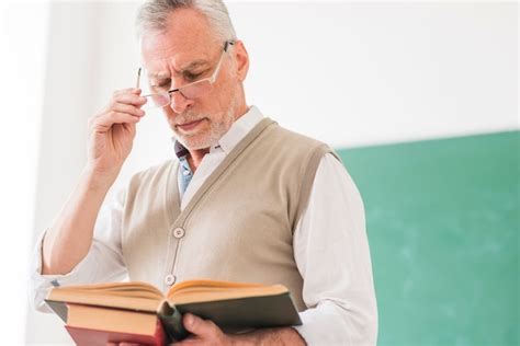 Free Photo Senior Male Professor Reading Book While Correcting Glasses