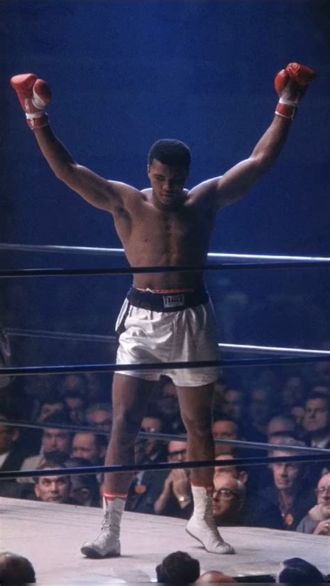 A Man Standing On Top Of A Wrestling Ring Holding His Hands Up In The Air