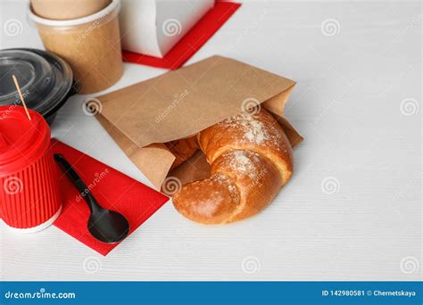 Paper Bag With Pastry And Takeaway Food On Wooden Table Stock Image