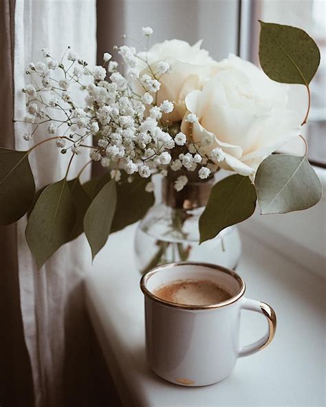 A Cup Of Coffee And Some Flowers On A Window Sill