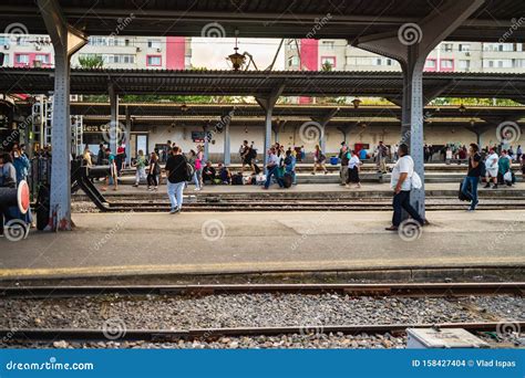 Travelers Waiting For A Train Sitting On A Bench On The Platform Of