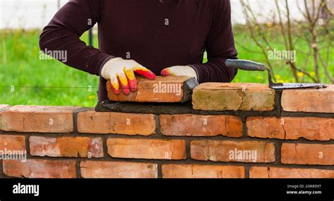 Un Hombre Construye Una Pared De Ladrillos Pone Un Ladrillo En Un