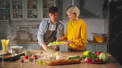 Beautiful Nice Blonde Woman Puts Chopped Vegetables Into A Glass Bowl