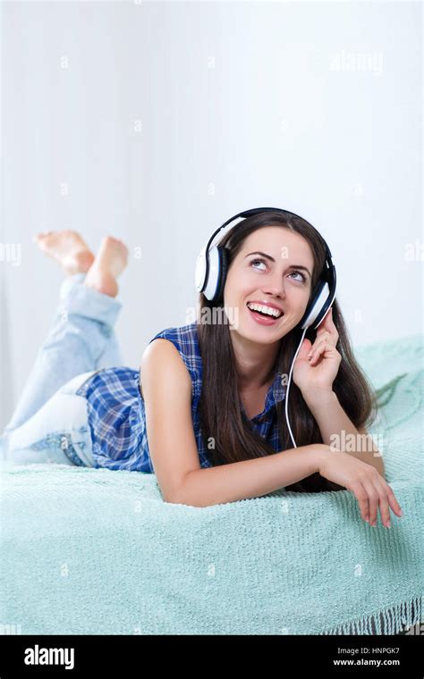 Happy Girl Listening Music Using Headphones And Singing On Bed At Home