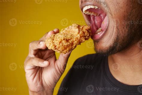 Man enjoying fried chicken, mouth open, savoring every bite with a big