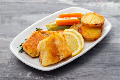 Fried Cod Fish With Lemon And Vegetables On White Plate Stock Image