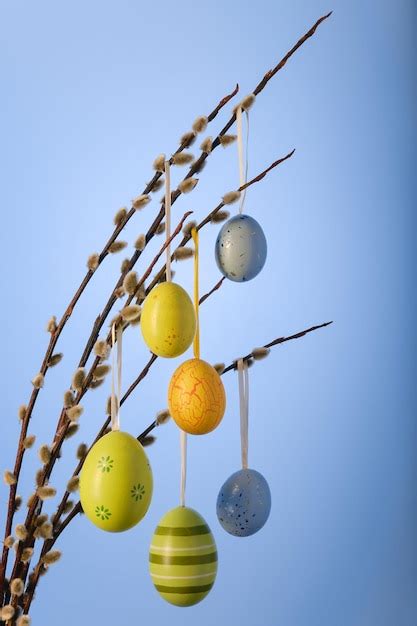Premium Photo Easter Pussy Willow Decorated With Colorful Easter Eggs Against Blue Background