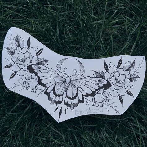 A White Butterfly With Flowers On It Sitting In The Grass