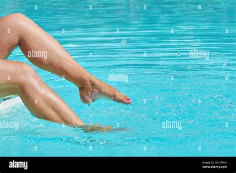 Closeup Of Female Barefoot Legs In Pool Splashing In Sunlight With