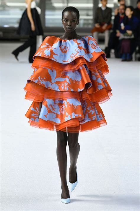 A Model Walks Down The Runway Wearing An Orange And Blue Dress With