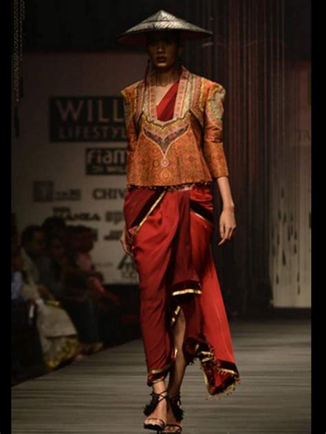 A Woman Wearing A Hat And Dress On The Runway