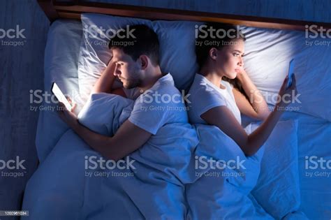 Cheating Spouses Using Smartphones Lying In Bed At Night Topview Stock