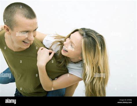 Young Couple Man Holding Young Woman On Back Looking Over Shoulder