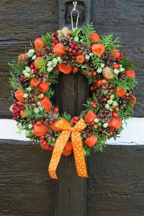 A Wreath With Pine Cones Berries And An Orange Bow Hangs On The Front Door