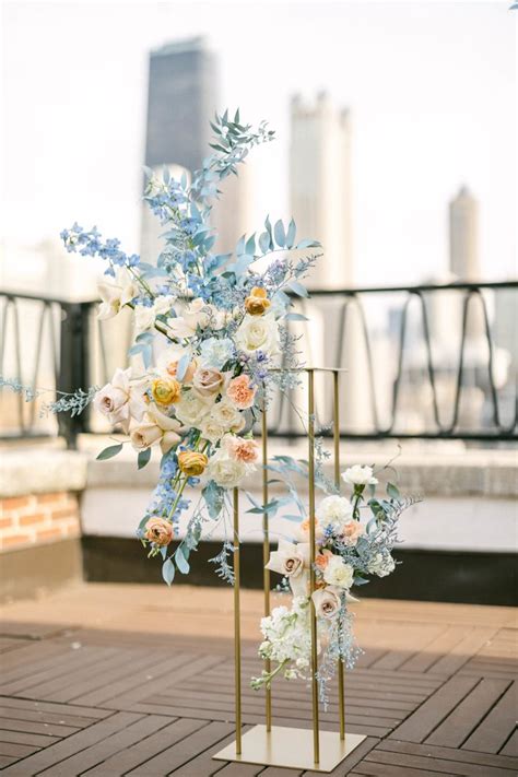 Two Tall Vases Filled With Flowers On Top Of A Wooden Floor