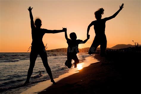 Silueta De La Familia Feliz Que Juega En La Playa En El Sunse Foto De