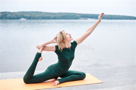 Young Blond Woman Wearing Green Overall With Bare Feet Doing Yoga Pose